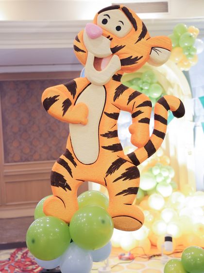 A life-sized Tigger cutout adds a fun and bouncy element to the Winnie the Pooh decor, standing cheerfully on a base of green and white balloons.