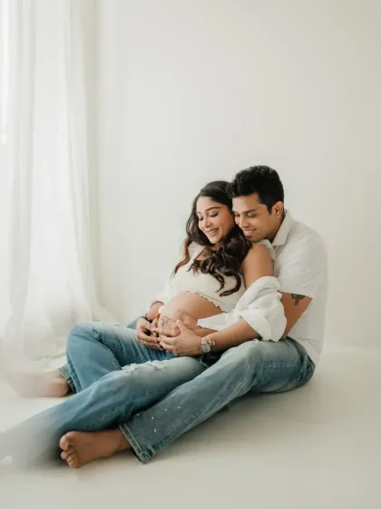 A cozy moment on the floor. This pose is great for creating a sense of intimacy and connection in a casual couples maternity shoot.