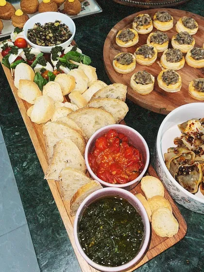Our Caprese-style grazing board is a fresh and light option. It features fresh mozzarella, cherry tomatoes, basil pesto, tomato confit, and slices of baguette for a build-your-own bruschetta experience.