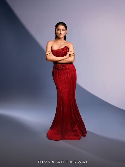 A full-length shot of the red Bellerose Gown, demonstrating its powerful and regal presence. The strapless corset design is both modern and timeless.