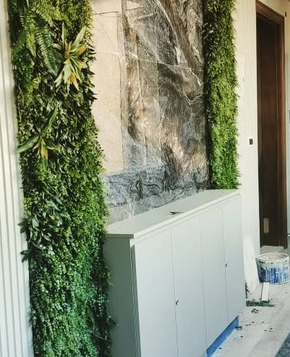 This design combines three different wall textures: white louvers, a central marble-effect panel, and two columns of lush artificial greenery, creating a sophisticated and modern feature wall.