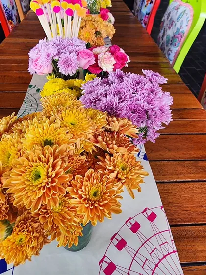 A close-up of the floral centerpieces on the long table, showcasing a rainbow of chrysanthemums and other colorful blooms.