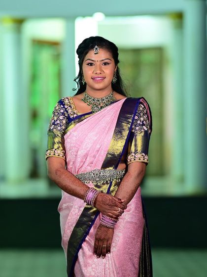 A full-length shot of Sneha. The elegant choker and matching vaddanam add a touch of modern sophistication to her pink silk saree.