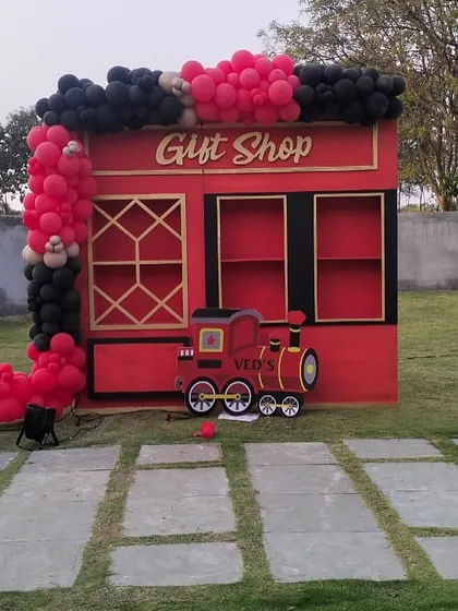 A detailed look at the gift shop booth from our Vedsvillie Station theme. The booth is framed by a red and black balloon garland, tying it into the overall train station concept and creating a fun, interactive area for guests.