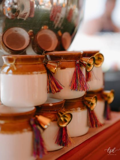 A charming detail of traditional 'matkas' adorned with colorful tassels and bells, used as unique and festive drinkware for the Mehendi.