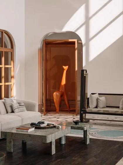 A detail shot of a sleek, modern swing with a woven cane back, set against an arched window. This piece combines traditional materials like cane and wood with a minimalist frame, showcasing our approach to contemporary Indian design.