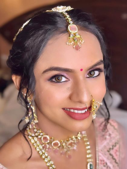 A portrait that captures her bright eyes and happy smile. The makeup is kept soft and romantic to match her pastel pink lehenga.