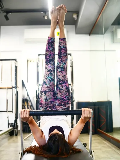 A client performs an inverted exercise on the reformer, a challenging move that requires significant core strength and control. This is a perfect example of how Pilates can be both graceful and powerful.