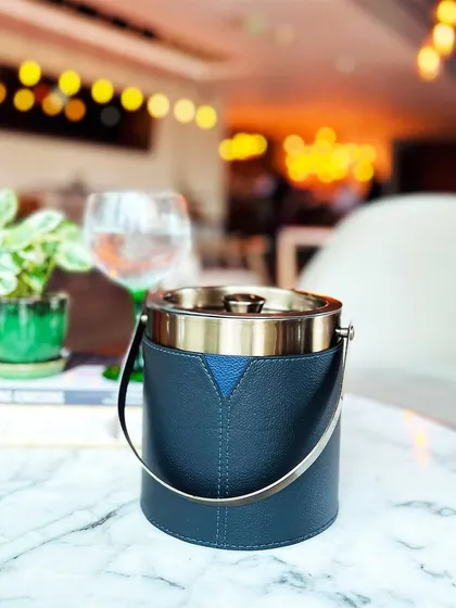 The perfect gift for the modern host. Our Bella Pelle Casa Ice Bucket, with its sleek design and timeless charm, is the ultimate accessory for any soirée, shown here adding sophistication to a cafe table setting.