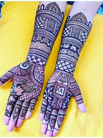 This design features a personalized touch with the initials 'AA' on the palm. The rest of the mehendi is filled with modern geometric patterns and lotus motifs.