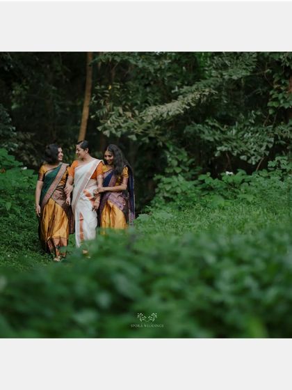 The bride and her friends walking through a lush green path, a candid shot full of natural beauty.