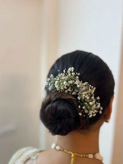 A clean and classic low bun decorated with baby's breath. This sophisticated hairstyle is perfect for an elegant saree look.