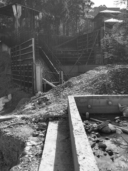 The reality of building on a steep slope in Himachal. This image shows the complex formwork required to create a terraced concrete structure that works with the mountain's gradient, not against it.