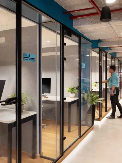 A closer look at the glass-walled cabins, which allow natural light to flow through the entire office. This layout supports a mix of individual and collaborative work modes.