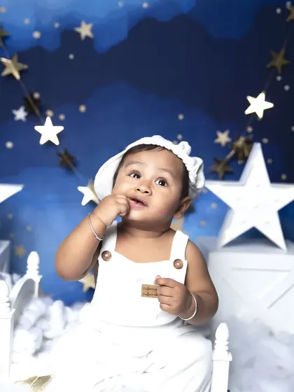 Looking up at the stars in this dreamy night-sky themed sitter session. The soft clouds and hanging stars create a serene and magical atmosphere.
