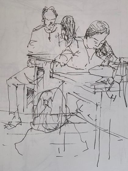 A quick, expressive line sketch of people sitting at a table, capturing a moment of rest and conversation at the festival.