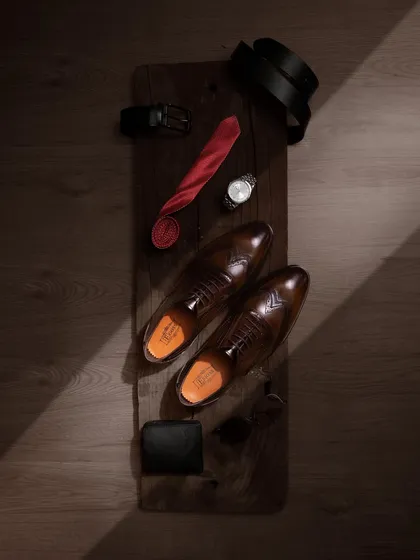 A top-down flat lay of men's formal accessories, with the leather shoes as the centerpiece. This type of shot is great for storytelling, suggesting a complete, sophisticated look for the modern gentleman.