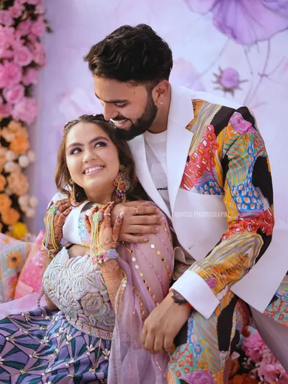 A sweet, candid moment between the couple, showcasing their vibrant wedding outfits and genuine affection.