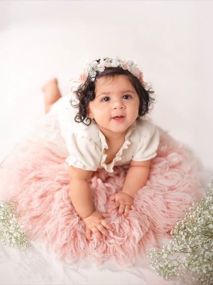 Lying on her tummy on a soft pink rug, this eleven-month-old looks right at the camera. This pose is great for showing off their strength and curiosity.