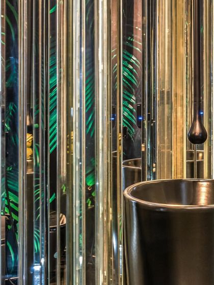 The powder room in Apartment 56 is designed as an immersive, glamorous experience. We used vertical strips of mirror and a backdrop of tropical wallpaper to create an infinite reflection of green, turning a small space into a bold artistic statement.