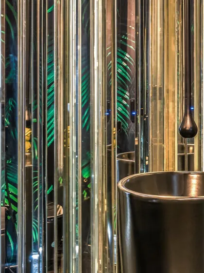 The powder room in Apartment 56 is designed as an immersive, glamorous experience. We used vertical strips of mirror and a backdrop of tropical wallpaper to create an infinite reflection of green, turning a small space into a bold artistic statement.
