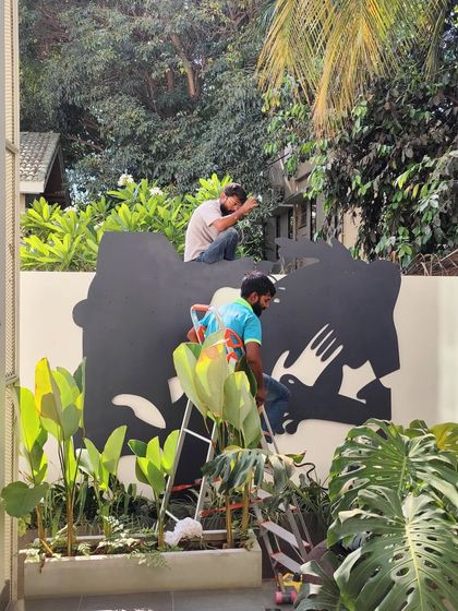 My team installing the large, black metal base shapes for the outdoor mural, showcasing the physical labor and precision required for our installations.