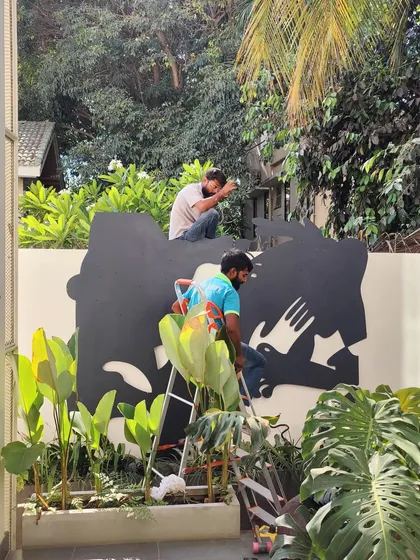 Our team installing a large-scale metal art piece on an outdoor wall, working around the existing landscape.