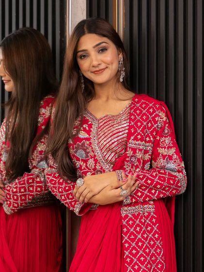 A smiling client looking fabulous in our red Indo-Western draped saree. It's the perfect blend of traditional color and modern silhouette.