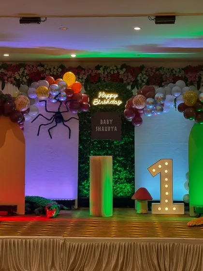 This jungle theme for baby Shaurya uses a different color palette with earthy tones and silver balloons. It shows how I can customize the theme to fit your preferences, complete with animal props and a light-up "1".