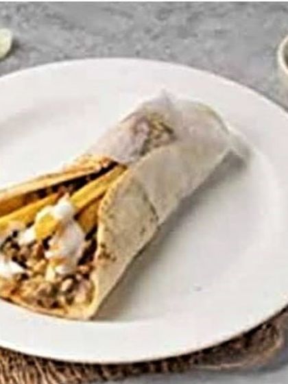 A close-up of a shawarma roll filled with chicken and fries, drizzled with my signature creamy garlic sauce.