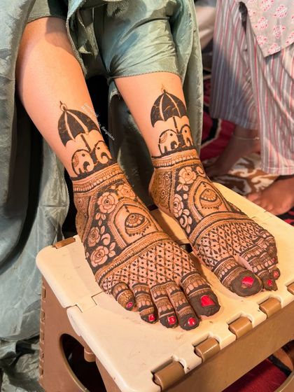 A unique and playful feet mehendi design. This pattern features two elephants holding an umbrella, a creative and charming choice for a bride.
