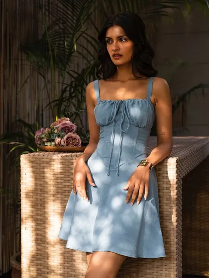 A sweet and simple summer dress, perfect for a casual day out. The soft blue color and the wicker table create a relaxed, cafe-culture vibe.