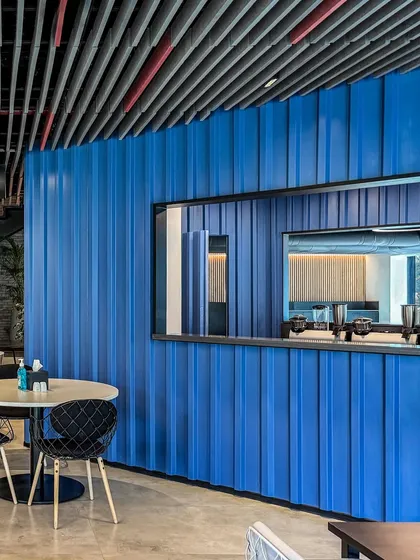 A bold blue corrugated wall adds a splash of color and industrial texture to the work lounge at BCG HQ, creating a memorable focal point.