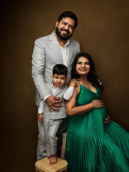 A beautiful family portrait celebrating the upcoming arrival. The older sibling-to-be is dressed to match his father, creating a charming and cohesive look.