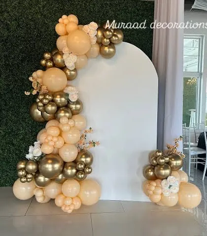 A simple yet beautiful balloon decoration for an outdoor or semi-outdoor venue. The arched backdrop is framed by an organic balloon garland in neutral beige and gold tones.