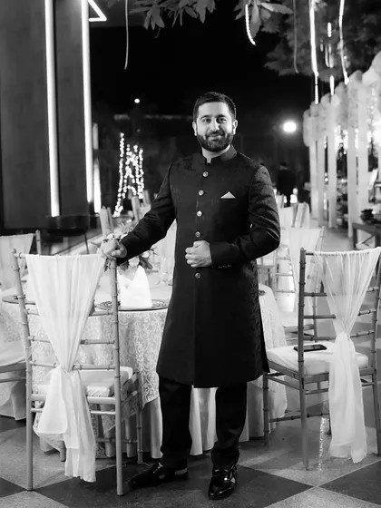 A dapper groom posing at his cocktail party. This black and white portrait captures his sharp attire and the elegant ambiance of the event.
