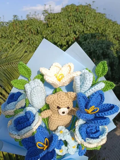 An example of a custom-made bouquet featuring a mix of blue and white flowers with an adorable amigurumi teddy bear nestled in the center. I love creating unique arrangements for special orders.