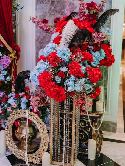 A closer look at the floral arrangements for the Masquerade party. We used a bold color palette of red, blue, and black, accented with pearls, feathers, and ornate gold frames for a touch of vintage glamour.