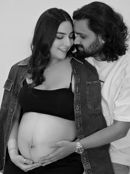 A close-up black and white shot, focusing on the couple's hands on the baby bump. It’s a beautiful, intimate detail.
