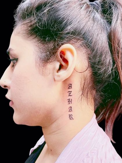 A name tattoo, "Azhar," in a unique font going down the side of the neck.