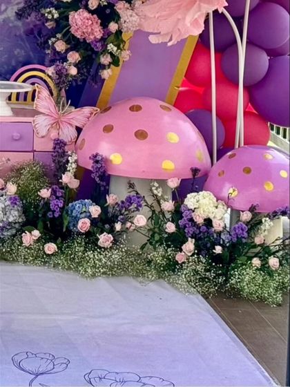 Whimsical, polka-dotted mushroom props add a touch of fairytale magic to the floral landscape.