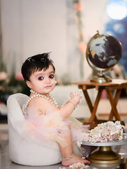 Our cake smash sessions are all about capturing your baby's curiosity and delight. This setup includes a miniature armchair and a globe prop, adding a touch of whimsy to the classic cake smash theme.