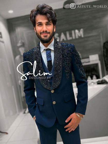 A client wearing a navy blue three-piece suit with heavily embellished lapels. The shawl collar design is a modern take on classic tuxedo styling.