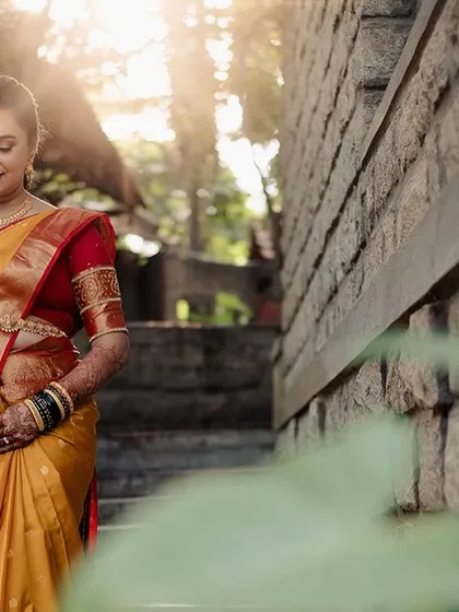 A bride descends a stone staircase, the golden hour light filtering through the leaves, creating a magical and radiant effect.