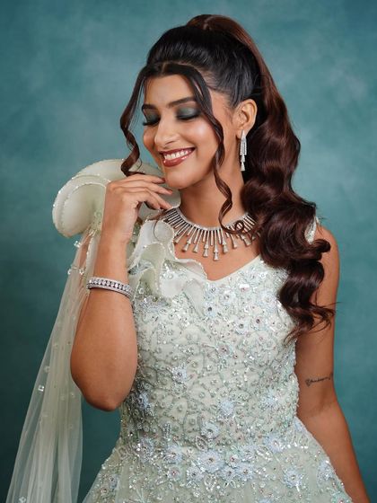 A glamorous high ponytail with soft, face-framing curls. This cocktail look is all about drama and sophistication, perfect for a bride who wants to make a statement at her reception or sangeet.