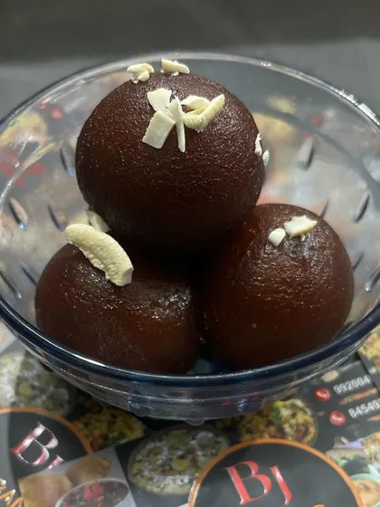 Soft, melt-in-your-mouth gulab jamuns, garnished with almond slivers. I prepare these using a traditional recipe to ensure authentic taste for your festive events.