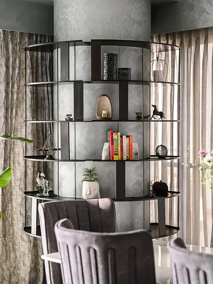 A detailed look at the custom shelving unit designed to wrap around a structural column. The dark metal frame and shelves provide a strong graphic element against the textured grey finish of the column, offering a stylish solution for display.