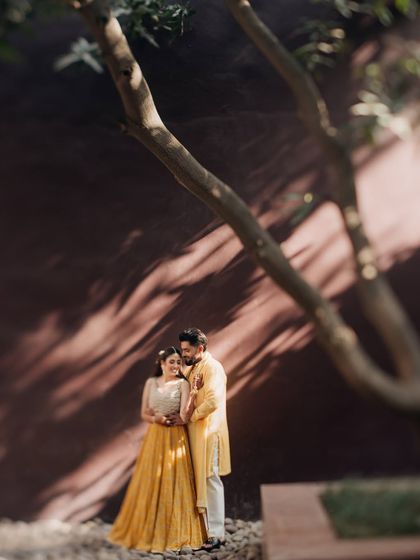 A romantic portrait of Shrey and Ragini under a tree during their Haldi celebration. The shadows and light create a beautiful, intimate atmosphere.