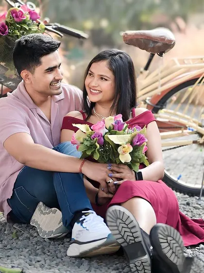 A sweet couple portrait with a vintage bicycle prop, set against a backdrop of tall grass. The flowers in the basket add a pop of color and romance to this outdoor engagement photo.