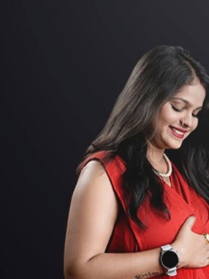 The simple joy of feeling your baby move. This close-up portrait in a bold red top against a dark background is intimate and full of emotion.